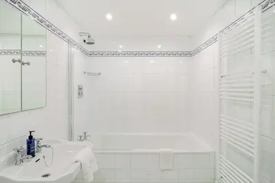 a white bathroom with a tub and a sink at Spacious Gleneagles Apartment