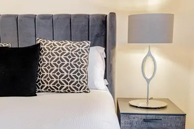 a bedroom with a bed with a lamp on a night stand at Spacious Gleneagles Apartment