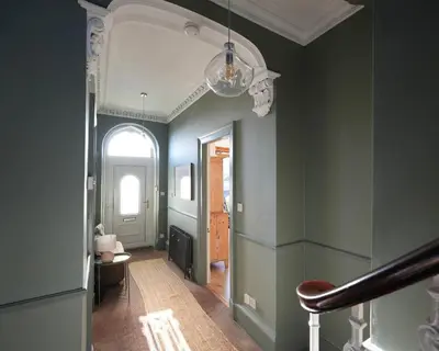 a hallway with green walls and a ceiling with a chandelier at Carmona Bank in Dunoon