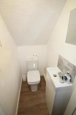 a white bathroom with a toilet and a sink at Beach Stroll Retreat, Swanage, Dorset in Moffat