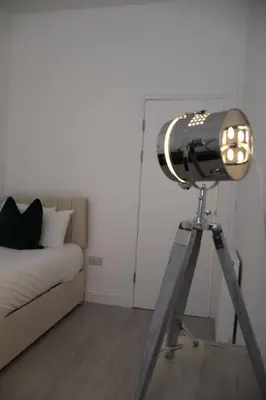 a light on a tripod in a room with a bed at Elegant 3BR Apt at Haymarket in Edinburgh