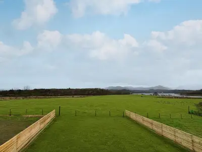 a large grassy field with a fence in the foreground at Eriska View in Port Appin