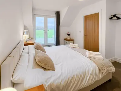 a white bedroom with a large bed and a window at Eriska View in Port Appin