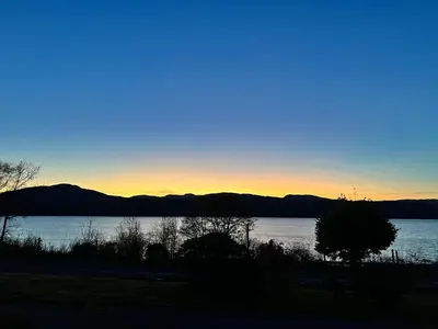 a sunset over a lake with mountains in the background at Oaktree Cottage, overlooking Loch Fyne in Cairndow