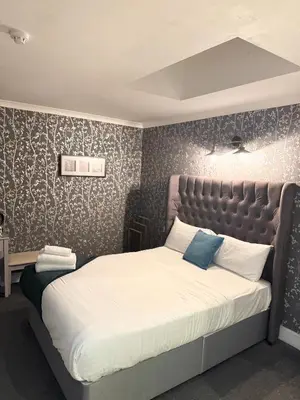 a bedroom with a large bed with a padded headboard at West Coates Mansion in Edinburgh
