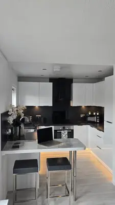 a kitchen with white cabinets and a table and chairs at Exceptional 1 bedroom riverside 2E apartment in Ayr