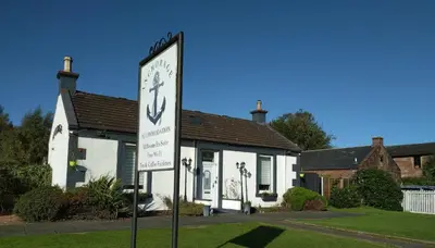 a sign in front of a house with a clock at Anchorage Accommodation in Balloch