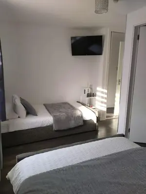 a bedroom with two beds and a tv on the wall at Anchorage Accommodation in Balloch