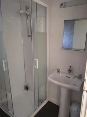 a white bathroom with a sink and a shower at Anchorage Accommodation in Balloch