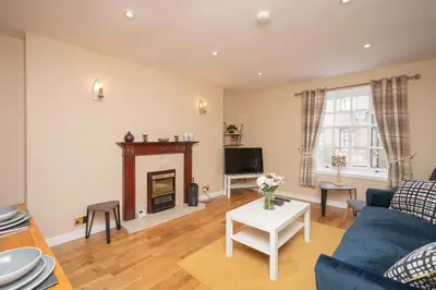 a living room with a blue couch and a fireplace at Bow Apartment in Stirling
