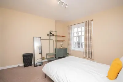 a bedroom with a bed and a mirror and a window at Bow Apartment in Stirling