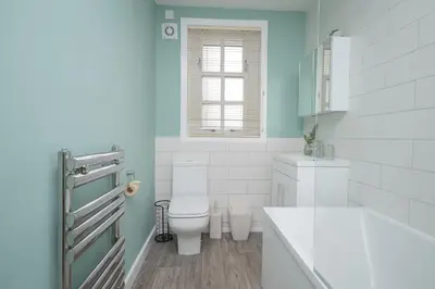 a white bathroom with a toilet and a window at Bow Apartment in Stirling