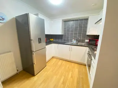 a kitchen with white cabinets and a stainless steel refrigerator at Paisley Central Apartment in Paisley