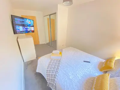 a bedroom with a bed and a flat screen tv at Paisley Central Apartment in Paisley