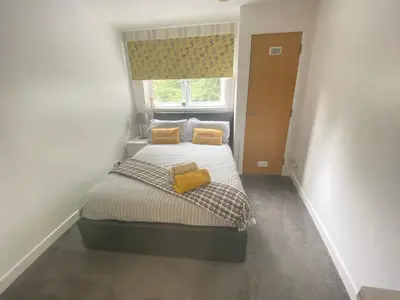 a small bedroom with a bed with two yellow pillows at Paisley Central Apartment in Paisley