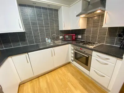 a kitchen with white cabinets and a sink and a stove at Paisley Central Apartment in Paisley