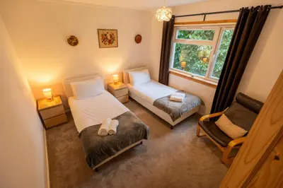 a bedroom with two beds and a chair and a window at Westwood in Oban