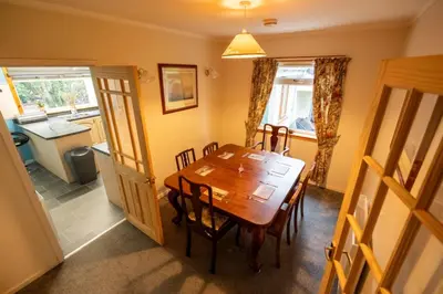 a dining room with a wooden table and a kitchen at Westwood in Oban