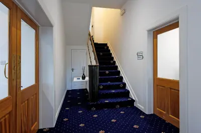 a hallway with a staircase with blue flooring and a door at Savoy 5 in Ayr