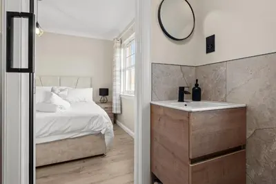 a bedroom with a bed and a sink and a mirror at The Riverside Rest 2 in Stirling