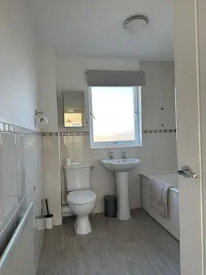 a bathroom with a toilet and a sink and a window at Lochside Hub in Balloch