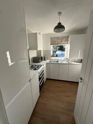 a kitchen with white cabinets and a stove top oven at Lochside Hub in Balloch