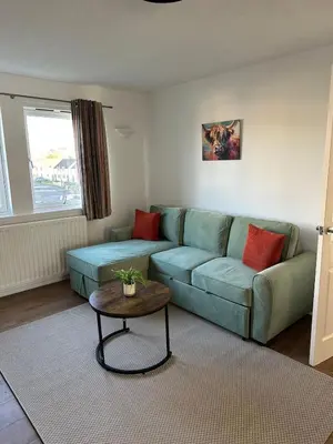 a living room with a green couch and a table at Lochside Hub in Balloch