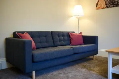 a blue couch with two pink pillows in a living room at The Oban Apartment in Oban