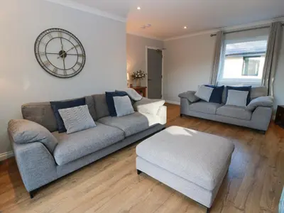 a living room with two couches and a clock on the wall at Cramar Cottage in Glasgow