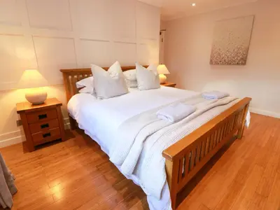 a bedroom with a large bed with white sheets and pillows at Cramar Cottage in Glasgow