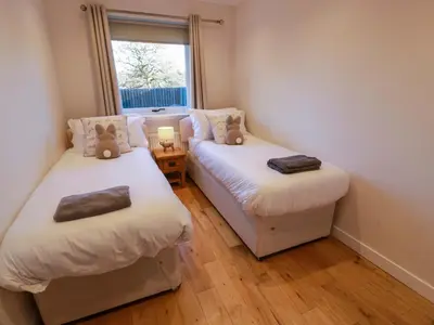 two twin beds in a room with a window at Cramar Cottage in Glasgow