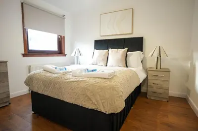a bedroom with a large bed with two containers on it at Nigel House in Livingston