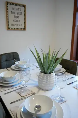 a table with plates and glasses and a potted plant at Nigel House in Livingston