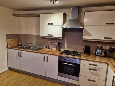 a kitchen with white cabinets and a stove top oven at Glasgow Southside Apartment in Glasgow