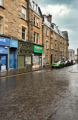 an empty city street with buildings and a green car at Modern 1-Bed Retreat by Stirling Train Station in Stirling