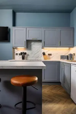 a kitchen with white cabinets and a wooden stool at Modern 1-Bed Retreat by Stirling Train Station in Stirling