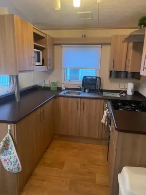 a small kitchen with wooden cabinets and a sink at Static Caravan 8 Berth 3 bedrooms, ensuite Saltcoats, Ayrshire, Scotland DG CH in Saltcoats
