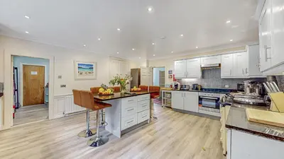 a large kitchen with white cabinets and a wooden floor at Finest Retreats - Ormidale House in Feorlean