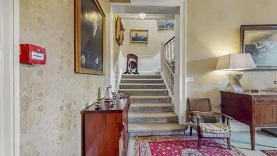 a hallway with a staircase with a chair and a table at Finest Retreats - Ormidale House in Feorlean