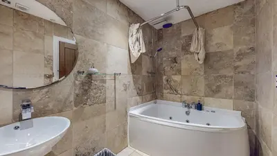 a bathroom with a tub and a sink and a mirror at Finest Retreats - Old Barn at Ormidale House in Clachan of Glendaruel