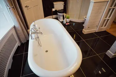 a white bath tub in a bathroom with black tiles at Bankhouse in Troon