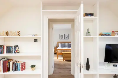 a room with white shelves with a television and a bedroom at JOIVY Lovely Flats in Edinburgh City Centre in Edinburgh