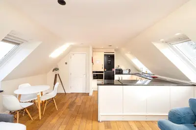 a kitchen with white cabinets and a table and chairs at JOIVY Lovely Flats in Edinburgh City Centre in Edinburgh