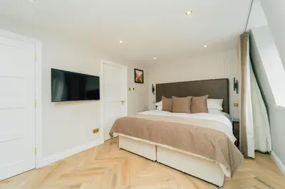 a bedroom with a large bed and a flat screen tv at Eagleside Apartments in Auchterarder