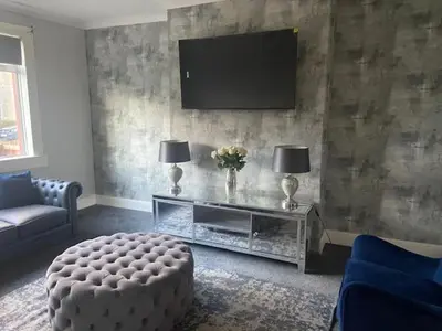 a living room with a television on a wall at 3BR Sleeps 6 Free Parking Near Glasgow City Centre in Renfrew