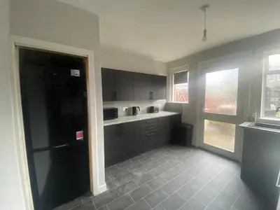 a kitchen with gray cabinets and a large window at 3BR Sleeps 6 Free Parking Near Glasgow City Centre in Renfrew