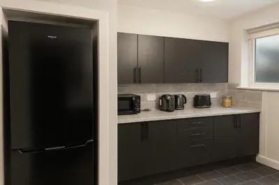 a kitchen with black cabinets and a black refrigerator at 3BR Sleeps 6 Free Parking Near Glasgow City Centre in Renfrew