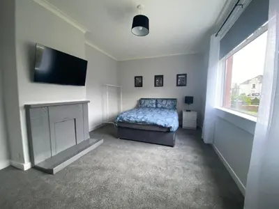 a bedroom with a bed and a flat screen tv at 3BR Sleeps 6 Free Parking Near Glasgow City Centre in Renfrew