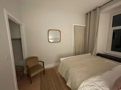a bedroom with a bed and a chair and a mirror at Cosy Coastal getaway 2 bed flat in Largs in Largs