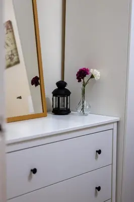 a dresser with a vase of flowers and a mirror at 53 Dorset street G3 7AG in Glasgow